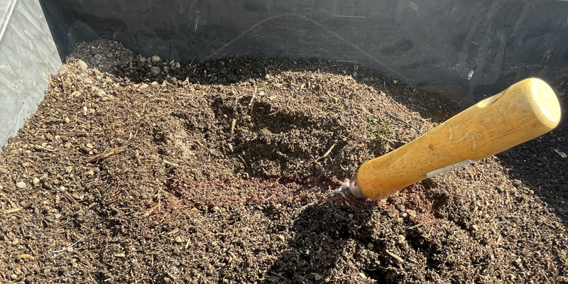 再生隅の土に熊手が刺さっている様子